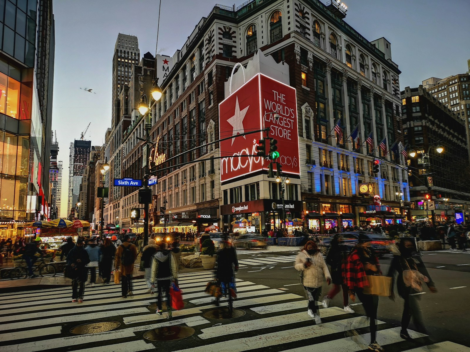 Crowds crossing at a busy Midtown Manhattan intersection at dusk